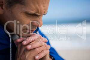 Mature man praying with hands clasped