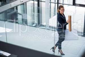 Businesswoman standing at office corridor with chart holder