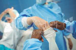 Female surgeon helping her co-worker in wearing surgical gloves