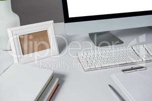 Picture frame, desktop pc and books on table