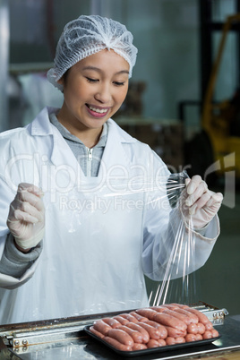 Female butcher packing raw sausages