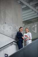 Businesswomen standing on staircase and using digital tablet
