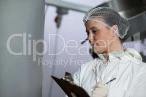 Female butchers maintaining records on clipboard