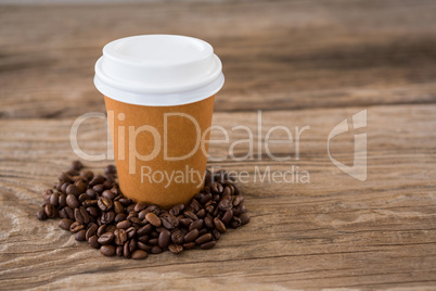 Coffee beans with disposable coffee cup on wooden table