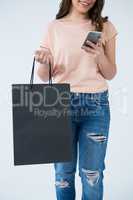 Woman carrying shopping bag and using mobile phone