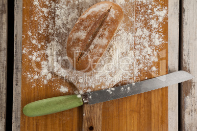 Bread loaf with knife on cutting board
