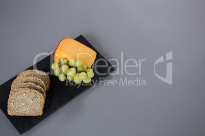 Gouda cheese, grapes and brown bread slices on slate plate