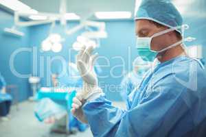 Male surgeon wearing surgical gloves in operation theater