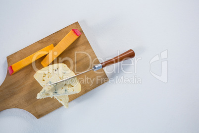 Variety of cheese with knife on wooden board