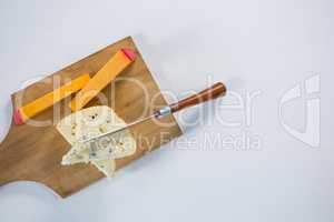 Variety of cheese with knife on wooden board