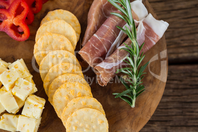 Cheese, red pepper slices, meat and nacho chips on wooden table