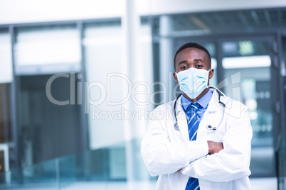 Doctor wearing surgical mask standing with hands crossed