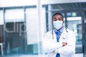 Doctor wearing surgical mask standing with hands crossed