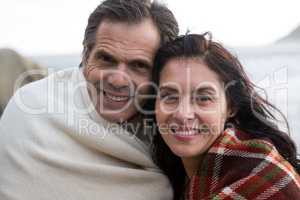 Portrait of happy couple wrapped in shawl on beach