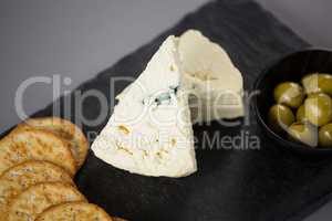 Pieces of cheese with biscuits and olives on slate plate