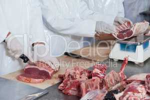 Butchers cutting meat and checking the weight of meat at meat factory