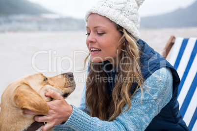 Woman pampering dog while sitting on chair