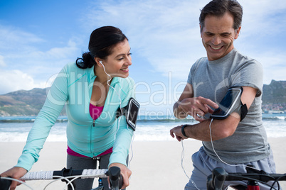 Couple leaning on bicycle while using mobile phone