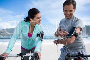 Couple leaning on bicycle while using mobile phone