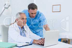 Surgeon and doctor discussing over laptop