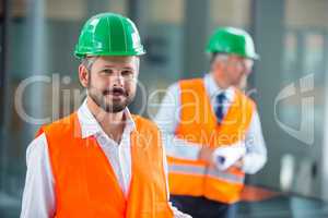 Architect in hard hat standing in office corridor