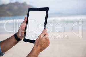 Close-up of mans hand using digital tablet on beach