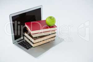 Laptop, stack of books and apple on white background