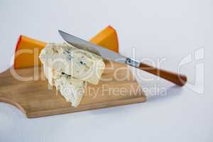Variety of cheese with knife on wooden board