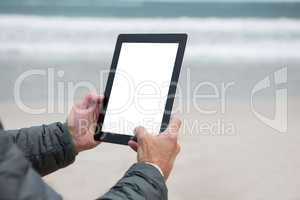 Man using digital tablet on beach