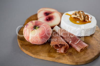 Peach with meat and brie cheese on wooden board