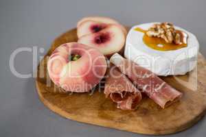 Peach with meat and brie cheese on wooden board