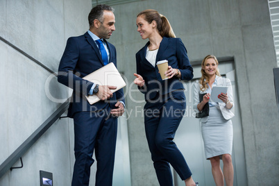 Business colleagues talking to each other while walking down stairs