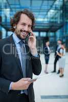 Businessman holding digital tablet talking on mobile phone