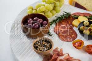 Variety of cheese with grapes, olives, salami and crackers