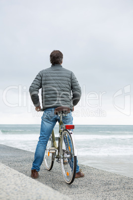 Rear view of man standing on bicycle