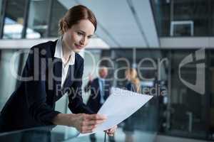 Businesswoman standing in corridor reading document in office