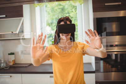 Beautiful woman using virtual reality headset in kitchen