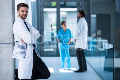 Doctor holding x-ray standing against the wall and smiling