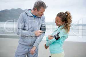 Couple using mobile phone while listening music on beach
