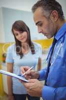 Doctor interacting with patient and writing on clipboard