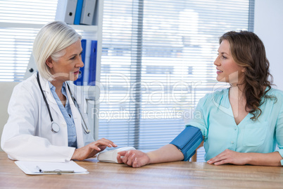 Female doctor checking blood pressure of a patient