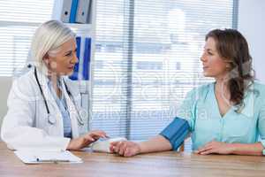 Female doctor checking blood pressure of a patient