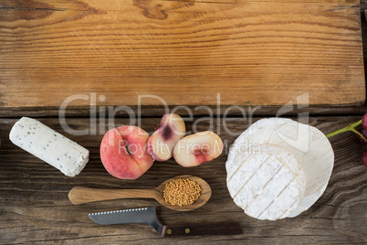 Variety of cheese with peach, spoon, knife and chopping board