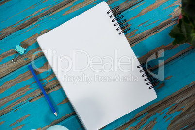 Notepad with pencil and paper clip on wooden table