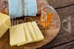 Slices of cheese, bread and fruit jam on wooden board