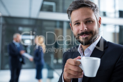 Businessman standing in office corridor with coffee cup