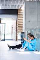 Stressed doctor and nurse sitting on floor examining X-ray report