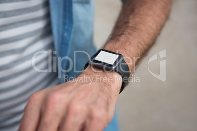 Mid section of man wearing smartwatch on beach
