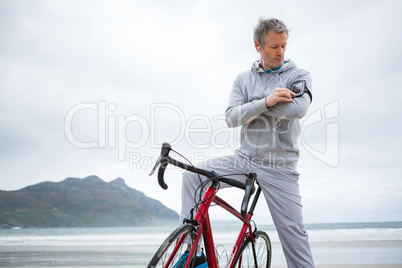 Man with bicycle listening music on mobile phone at beach