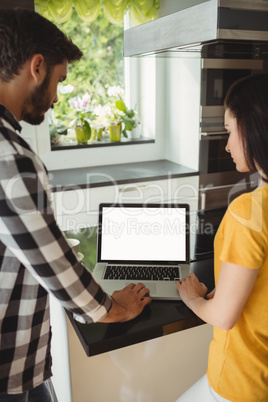 Couple using laptop in the kitchen